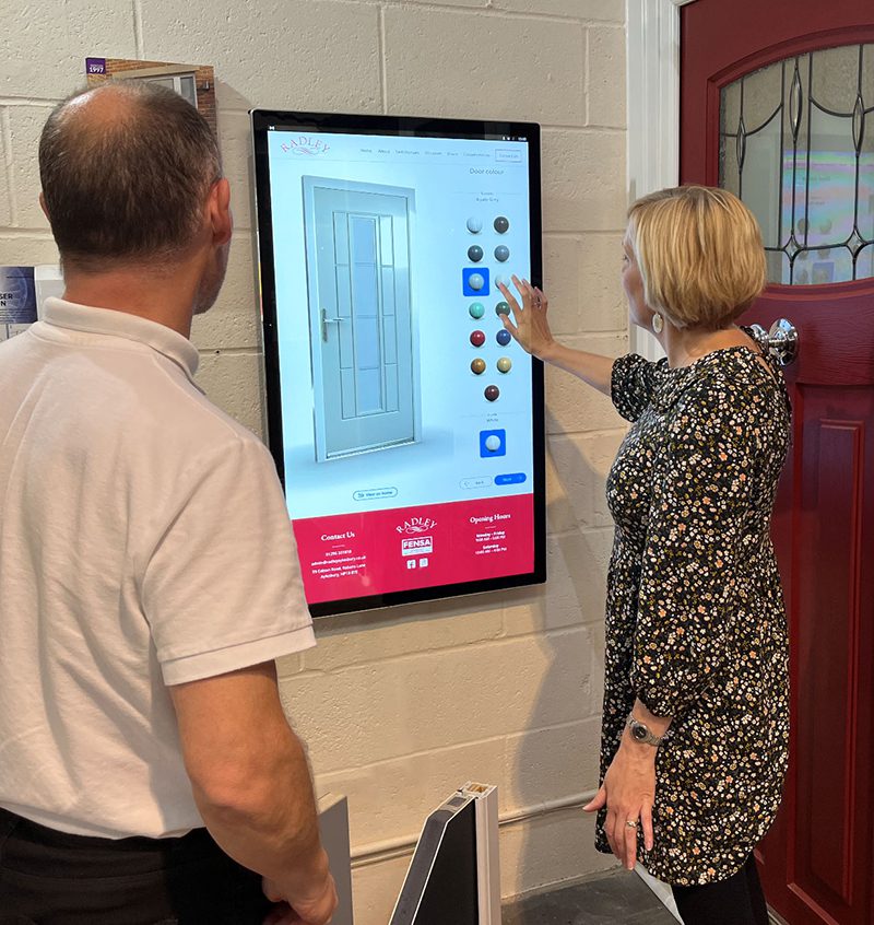 Écran tactile mural en collectivité utilisé par un citoyen pour un configurateur en libre-service